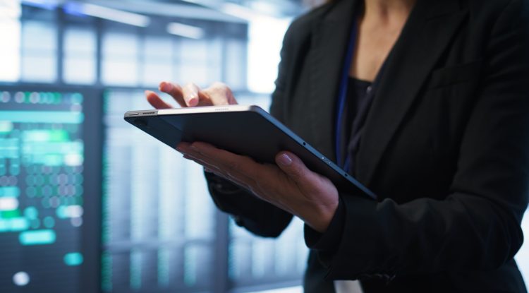 Computer scientist managing data center with advanced technology using digital device. Close up shot of person in server room optimizing data center gear with tablet, camera B