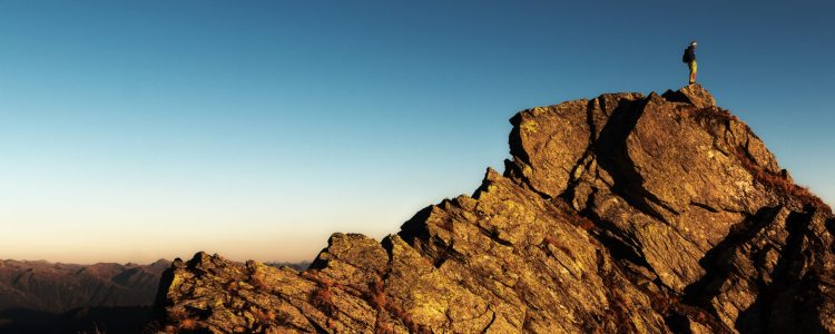 Man Standing on Top of Rock at Daytime